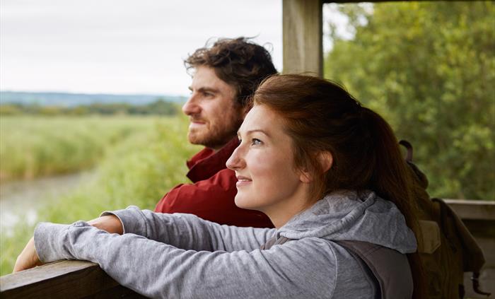 Visitors looking out at wetlands from a hide at WWT Llanelli
